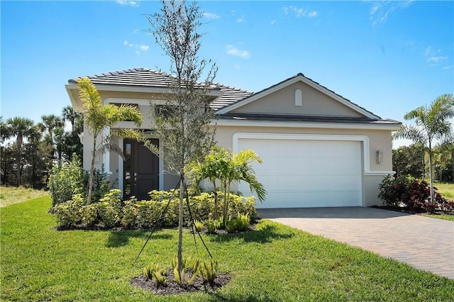 view of front facade featuring an attached garage, a tile roof, decorative driveway, stucco siding, and a front lawn