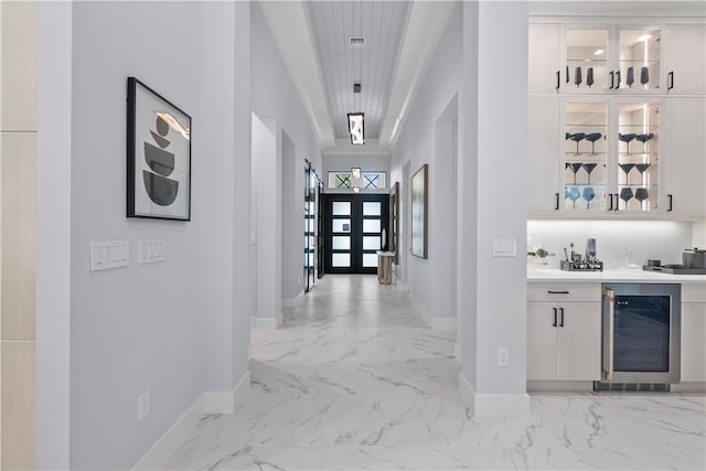 9259 Seaglass Ct, Vero Beach, FL 32963 - hallway with beverage cooler, baseboards, light marble finish flooring, and french doors