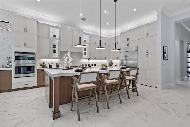 9259 Seaglass Ct, Vero Beach, FL 32963 - kitchen with appliances with stainless steel finishes, light marble finish flooring, a kitchen island with sink, a kitchen bar, and light countertops