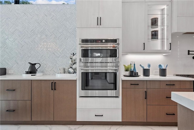 9259 Seaglass Ct, Vero Beach, FL 32963 - kitchen with double oven, light countertops, modern cabinets, marble finish flooring, and tasteful backsplash