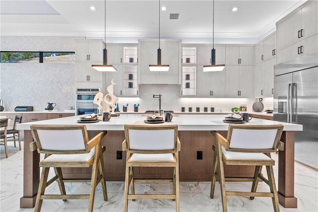 9259 Seaglass Ct, Vero Beach, FL 32963 - kitchen with light marble finish floors, appliances with stainless steel finishes, light countertops, an island with sink, and a kitchen bar