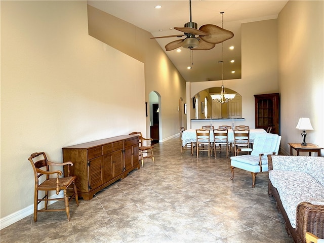 interior space with high vaulted ceiling and ceiling fan with notable chandelier