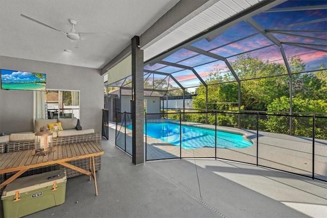 pool at dusk featuring a patio area, an outdoor hangout area, and glass enclosure