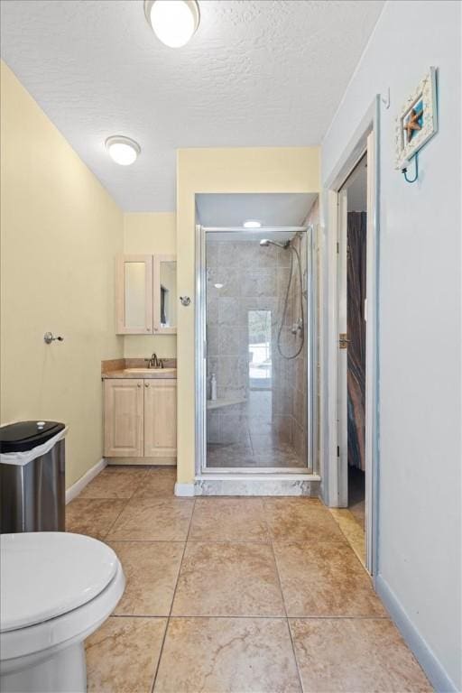 bathroom featuring toilet, a shower with door, vanity, and a textured ceiling