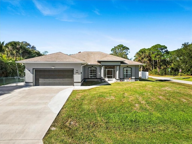 view of front facade with a garage, fence, driveway, stucco siding, and a front yard