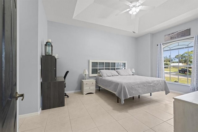 bedroom with light tile patterned flooring, ceiling fan, and a tray ceiling