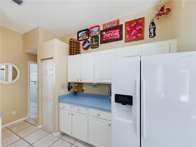 kitchen with white cabinets, white refrigerator with ice dispenser, and light tile patterned floors