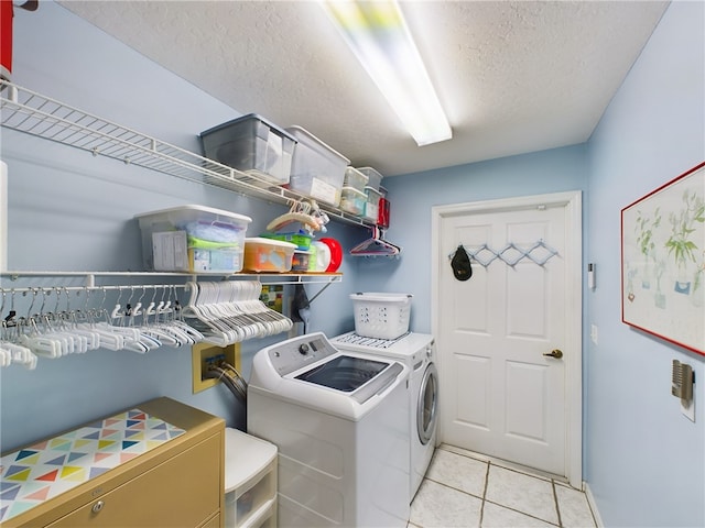 laundry room featuring light tile patterned flooring, a textured ceiling, and washing machine and clothes dryer