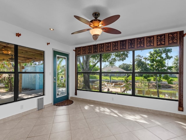 empty room featuring a healthy amount of sunlight, ceiling fan, and light tile patterned floors