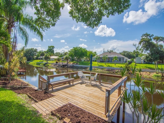 view of dock featuring a lawn and a water view