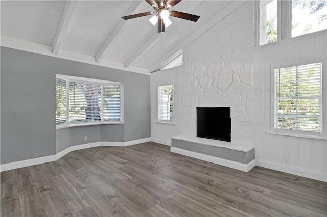 705 10th Ave SW, Vero Beach, FL 32962 - unfurnished living room featuring ceiling fan, beam ceiling, wood finished floors, a stone fireplace, and high vaulted ceiling
