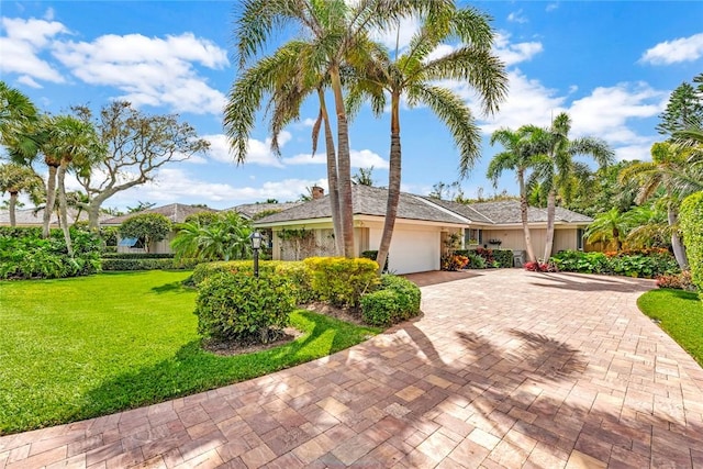 ranch-style home with a front yard, decorative driveway, and an attached garage