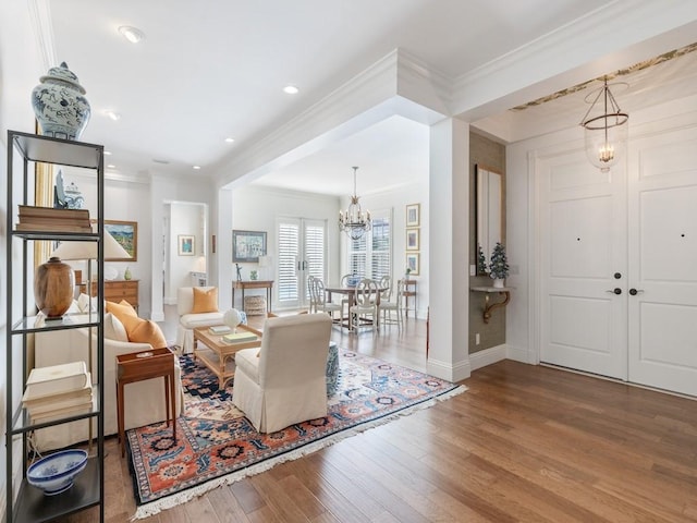 living room with ornamental molding, a notable chandelier, and hardwood / wood-style flooring