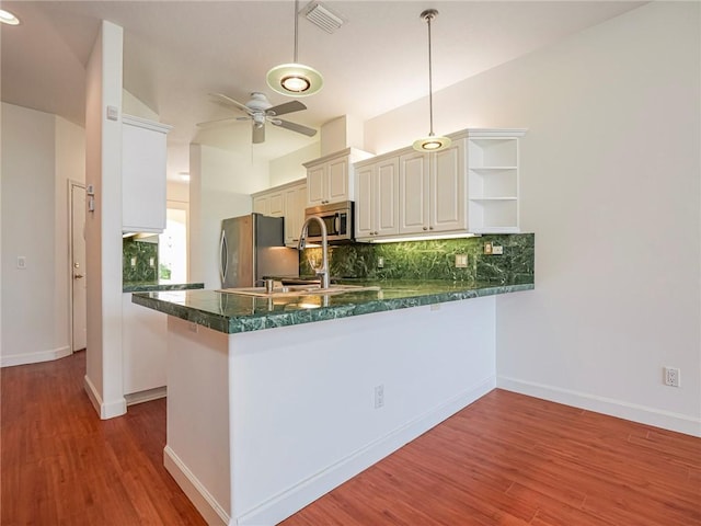 kitchen featuring decorative light fixtures, backsplash, hardwood / wood-style flooring, kitchen peninsula, and stainless steel appliances