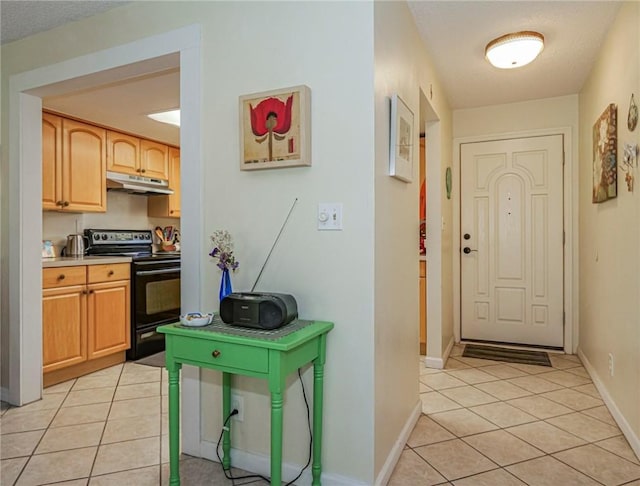 kitchen featuring light tile patterned floors, black / electric stove, baseboards, light countertops, and under cabinet range hood