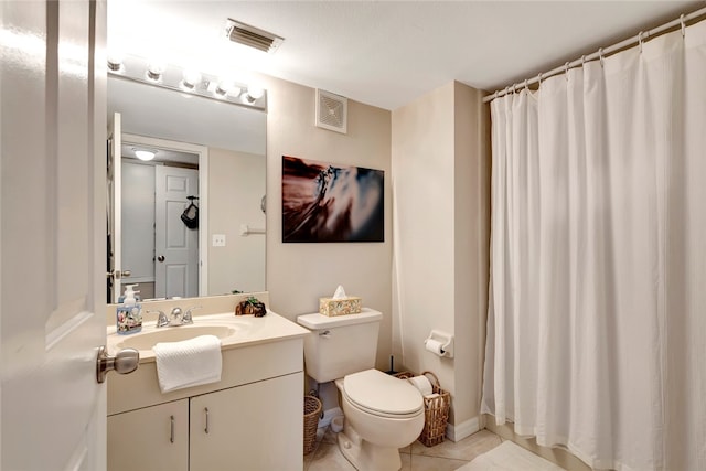 bathroom with toilet, vanity, and tile patterned floors