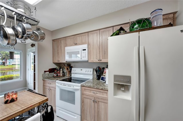 kitchen featuring light brown cabinets, light stone counters, a textured ceiling, and white appliances