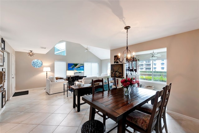 dining room with ceiling fan with notable chandelier, a wealth of natural light, lofted ceiling, and light tile patterned floors