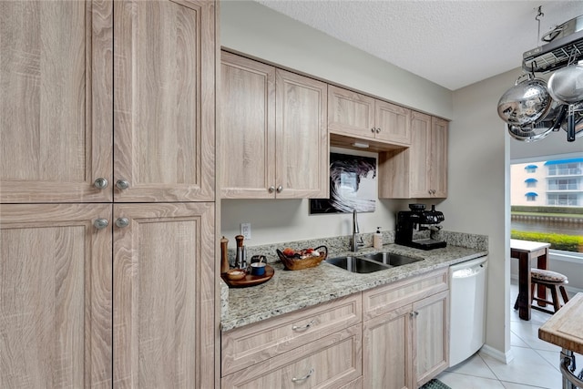 kitchen featuring light tile patterned flooring, sink, light brown cabinets, a textured ceiling, and dishwasher