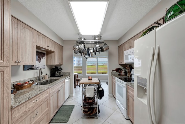 kitchen with a textured ceiling, light tile patterned floors, light brown cabinets, sink, and white appliances