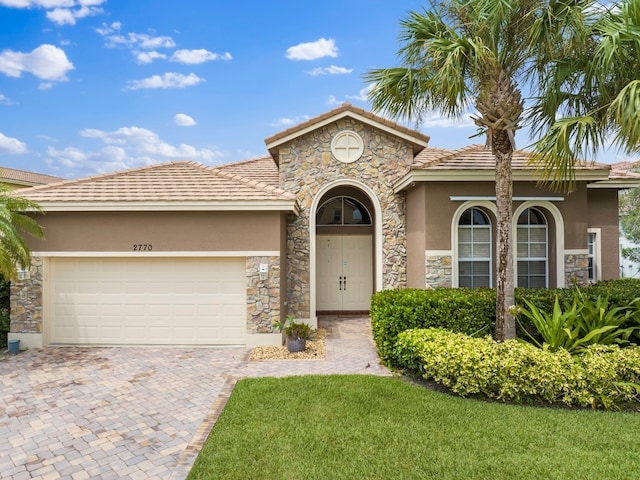 mediterranean / spanish home featuring a garage and a front lawn