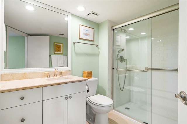 bathroom featuring vanity, a shower with door, tile patterned floors, and toilet