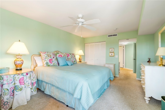 bedroom with ceiling fan, light carpet, and a closet