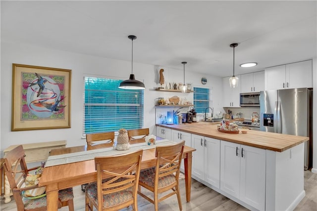 kitchen with decorative light fixtures, white cabinets, appliances with stainless steel finishes, and sink