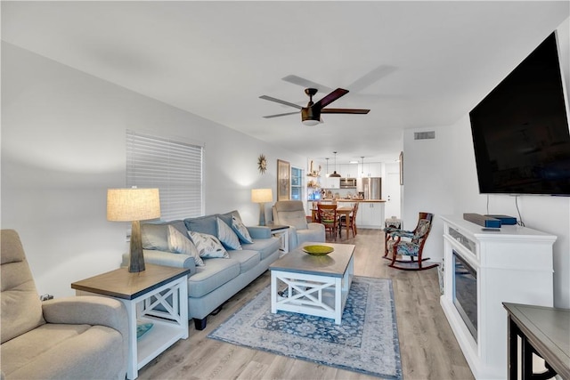 living room with ceiling fan and light wood-type flooring