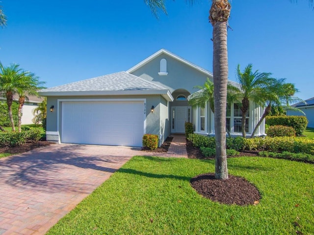 8340 Paladin Sq, Vero Beach, FL 32967 - view of front of house featuring stucco siding, an attached garage, decorative driveway, and a front lawn
