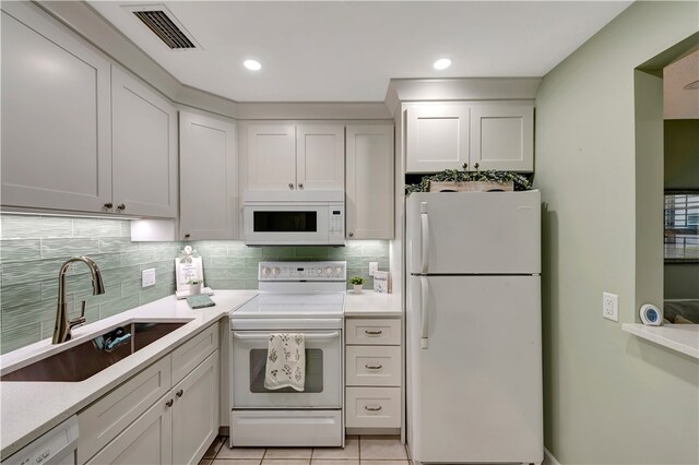 kitchen with white cabinets, sink, light tile patterned floors, backsplash, and white appliances