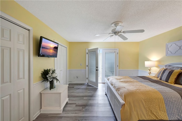 bedroom featuring a textured ceiling, dark hardwood / wood-style floors, ceiling fan, and two closets