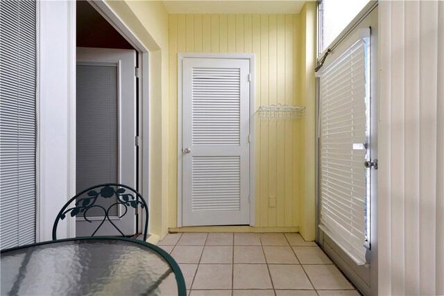 entryway featuring wooden walls and light tile patterned floors