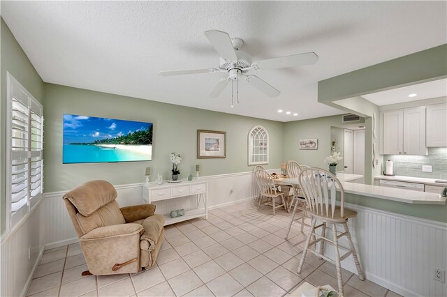 living room with a textured ceiling, light tile patterned flooring, and ceiling fan