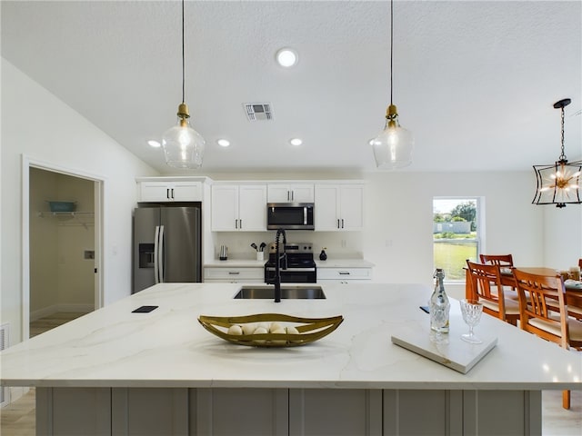kitchen with visible vents, a spacious island, a sink, stainless steel appliances, and white cabinetry