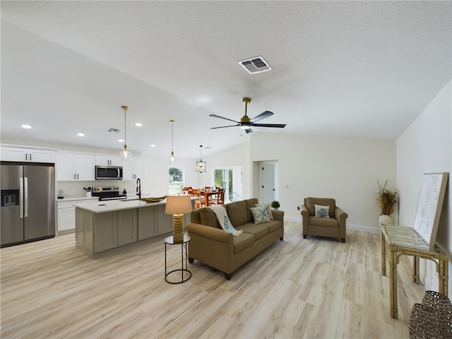 living room featuring visible vents, a ceiling fan, light wood finished floors, and lofted ceiling