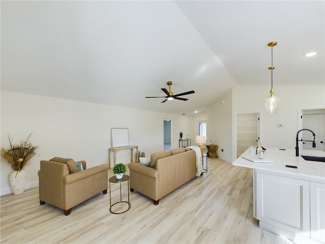 living area featuring light wood-style floors, a ceiling fan, baseboards, and lofted ceiling