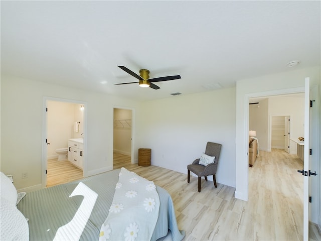 bedroom with ceiling fan, a walk in closet, light wood finished floors, ensuite bath, and visible vents