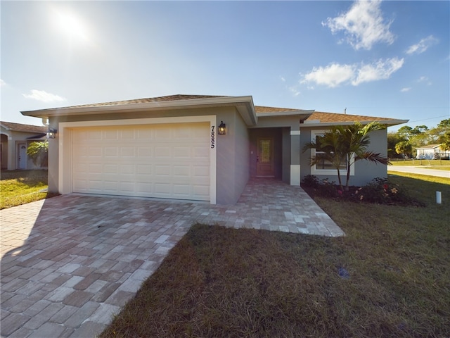 view of front of home featuring decorative driveway, a garage, stucco siding, and a front yard