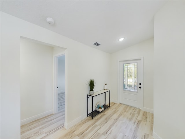 foyer with baseboards, light wood-style flooring, and lofted ceiling