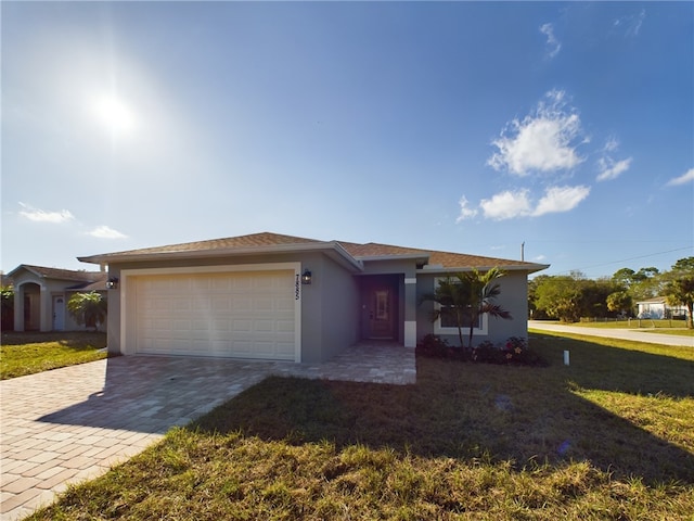 view of front of house with decorative driveway, an attached garage, a front lawn, and stucco siding