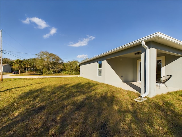 view of home's exterior featuring a lawn, stucco siding, and a patio area