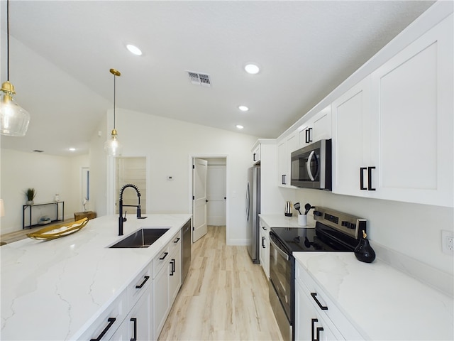 kitchen featuring appliances with stainless steel finishes, a sink, visible vents, white cabinetry, and vaulted ceiling