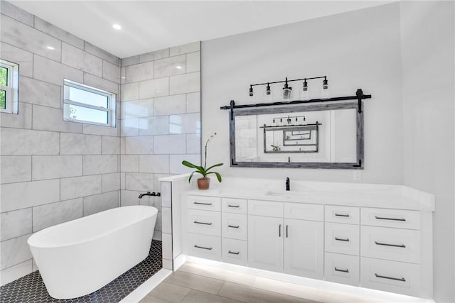 7205 Kamelya St SW, Vero Beach, FL 32968 - bathroom featuring vanity, tile walls, recessed lighting, a soaking tub, and tile patterned floors