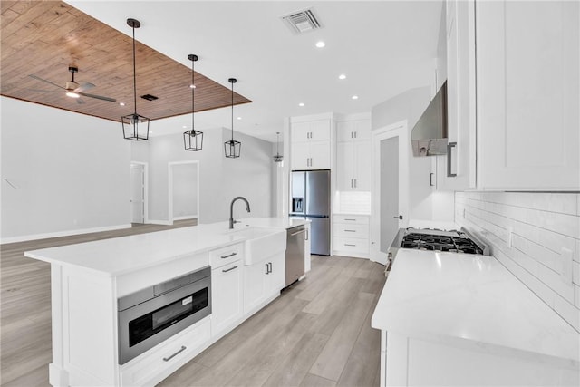 7205 Kamelya St SW, Vero Beach, FL 32968 - kitchen with visible vents, wall chimney exhaust hood, appliances with stainless steel finishes, light wood-style floors, and backsplash