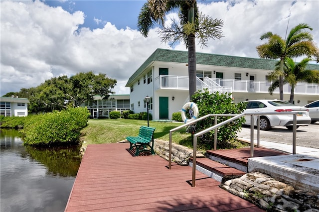 dock area featuring a yard, a water view, and a balcony