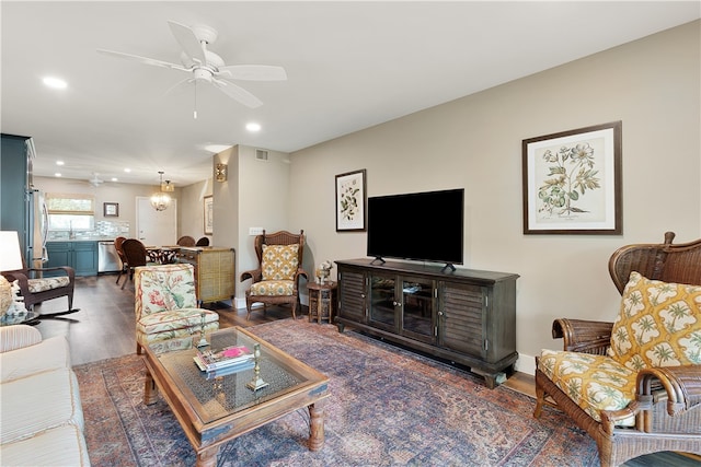 living room with dark wood-type flooring and ceiling fan with notable chandelier