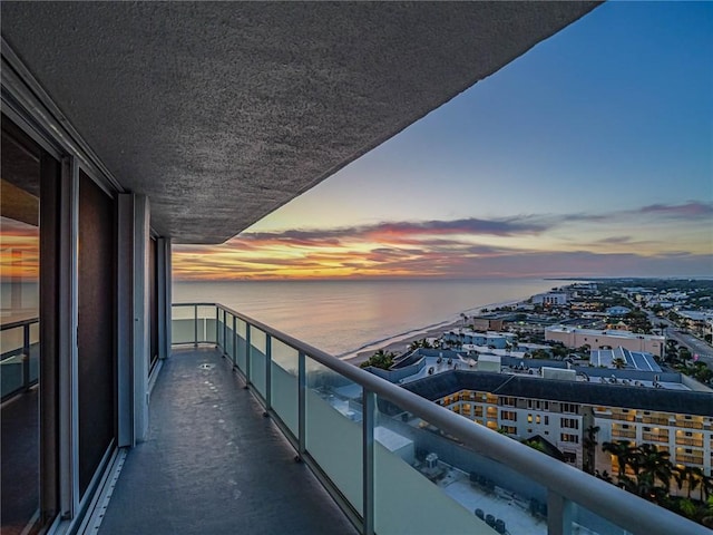 balcony at dusk featuring a water view