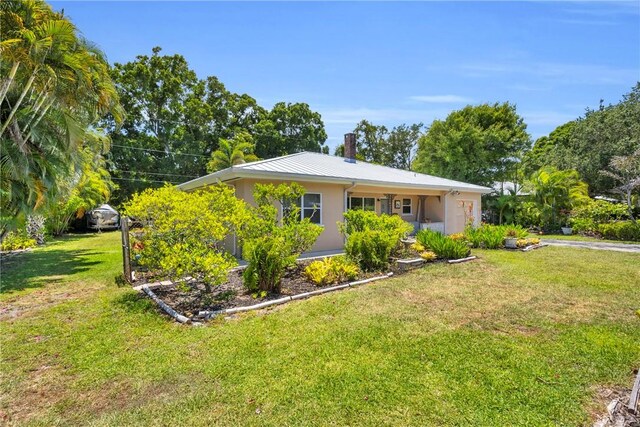 843 22nd Pl, Vero Beach, FL 32960 - single story home with a front yard, a metal roof, stucco siding, a chimney, and a standing seam roof