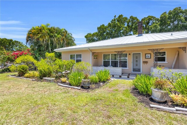 843 22nd Pl, Vero Beach, FL 32960 - view of front facade featuring a front yard, a chimney, stucco siding, and a metal roof